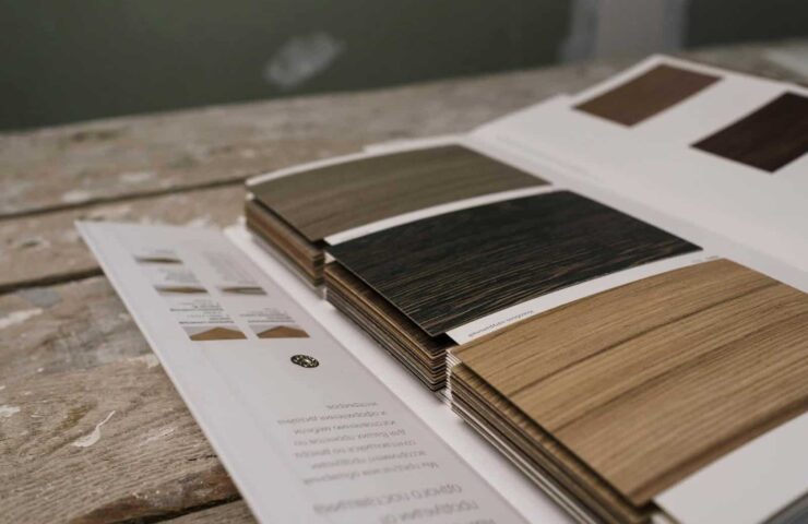Collection of wood veneer samples displayed on a rustic wooden table indoors.
